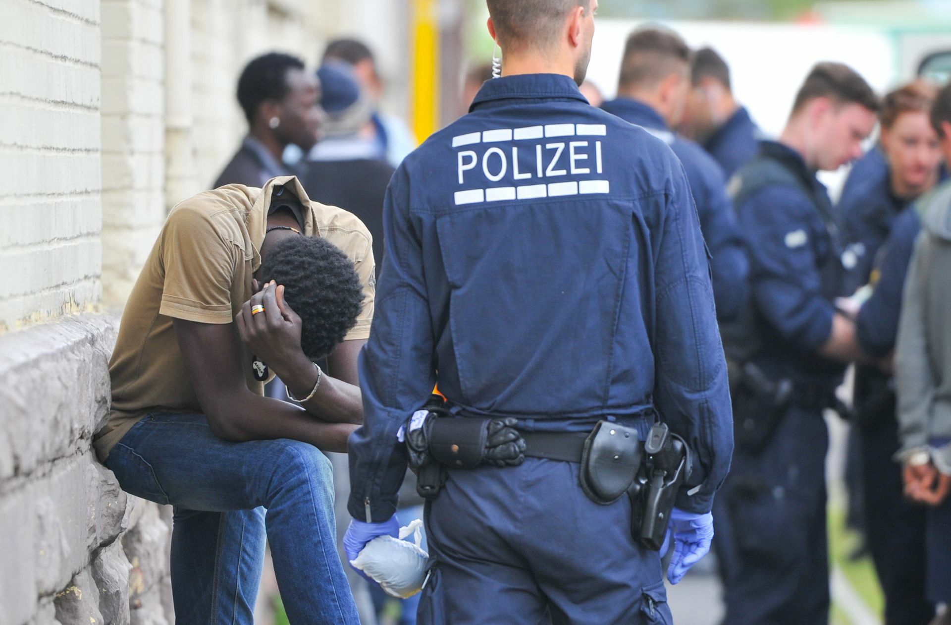 Polizisten überwachen während einer Drogenrazzia in einer Landeserstaufnahmestelle Verdächtige. Foto: dpa/Uwe Anspach