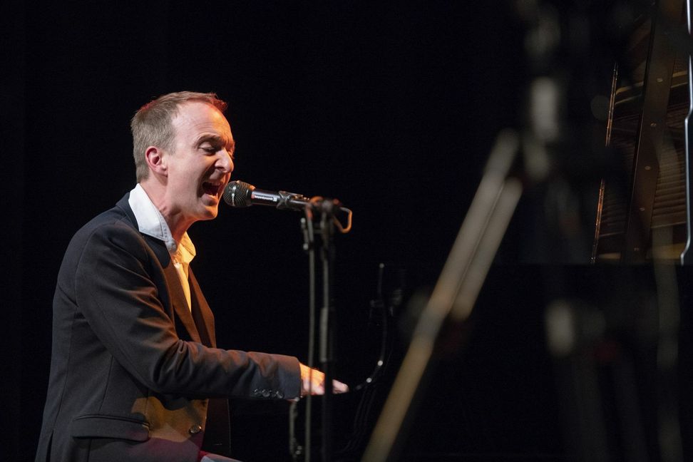 Patrick Bopp alias Memphis der Vocalband "Füenf" gibt den musikalischen Moderator am Klavier, singt vor und motiviert. Gesungen wird ohne Noten, der Text wird auf die Bühnenleinwand projiziert.   Bild: z