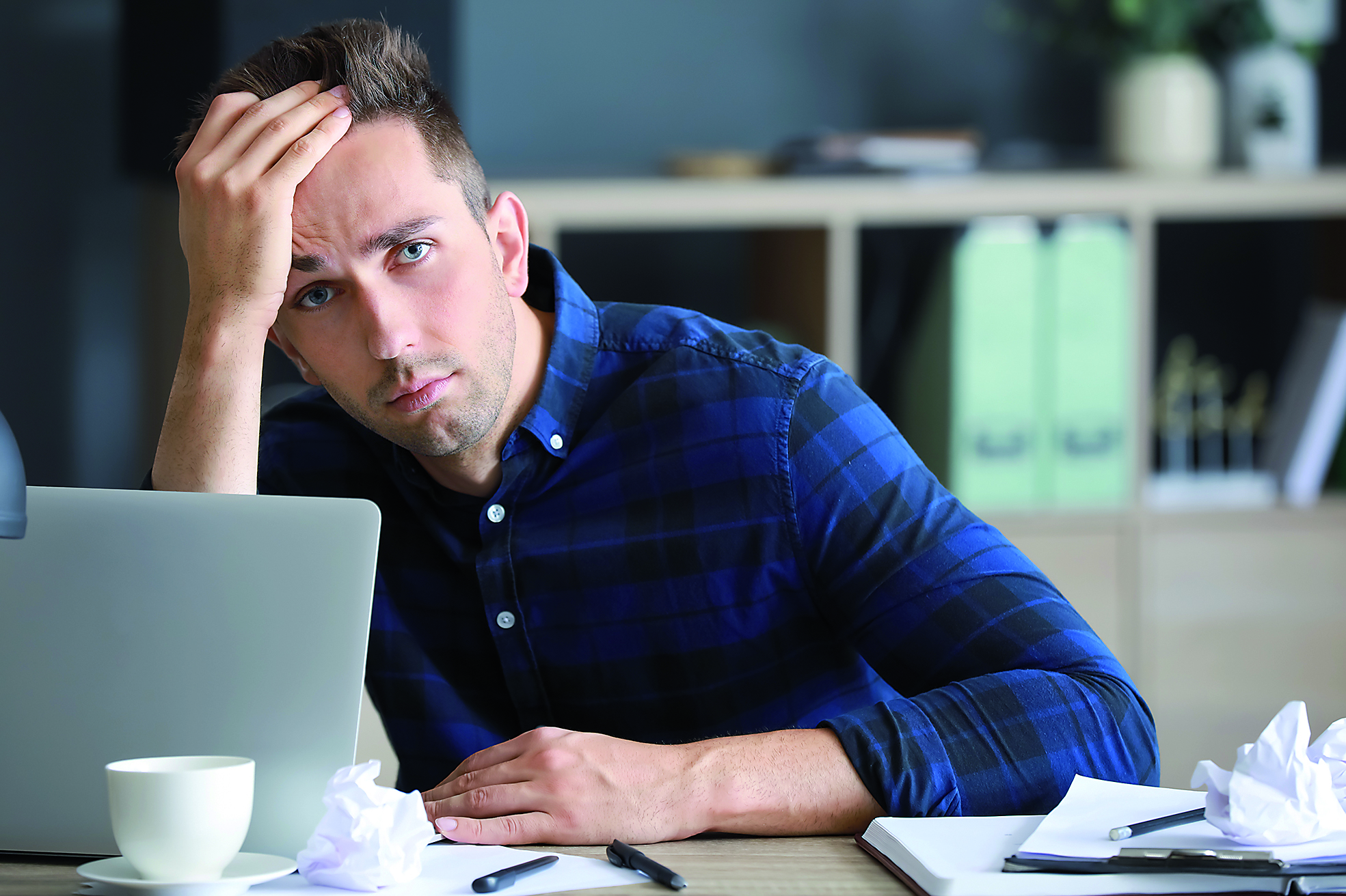 Stressed young man at table in office