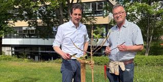 Martin Wuttke und Manfred Nuber pflanzen einen Apfelbaum.