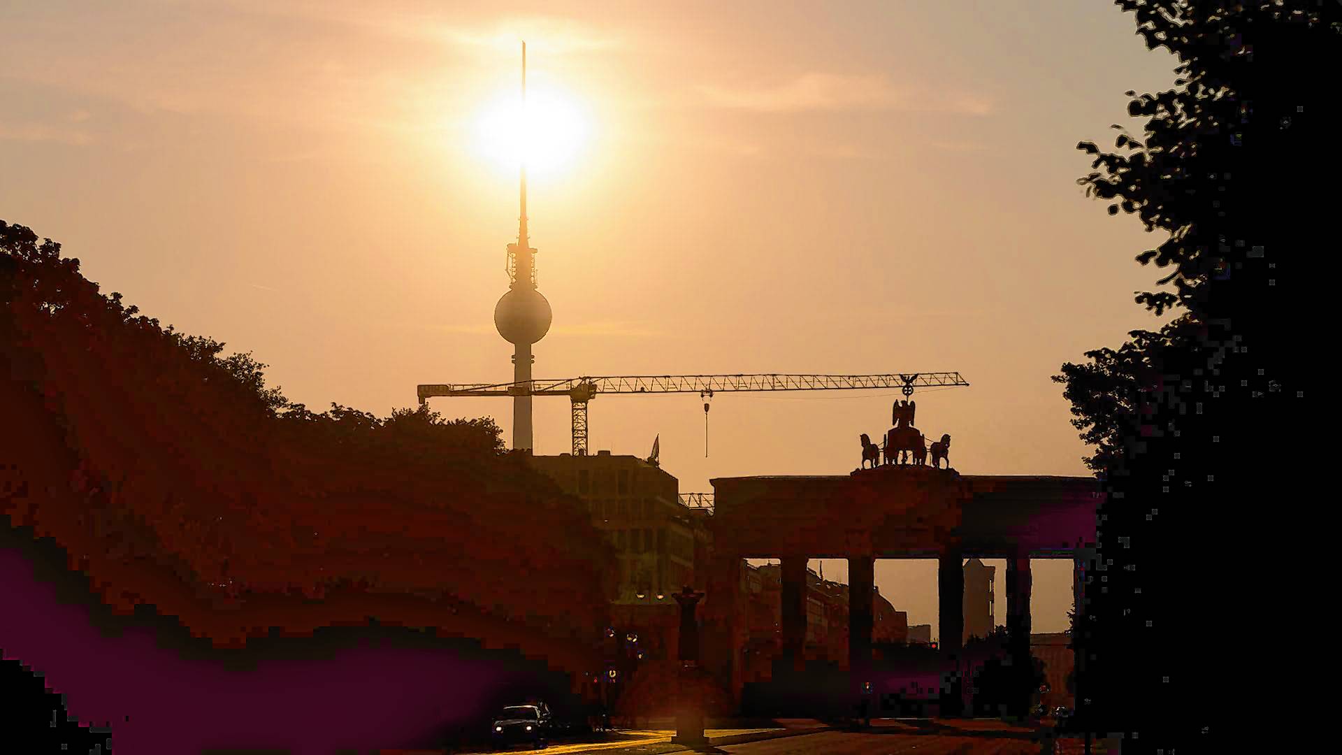 Das Brandenburger Tor und der Fernsehturm sind im Gegenlicht der aufgehenden Sonne zu sehen. Am Montag zeigt sich laut Vorhersage meist die Sonne, höchstens wird es locker bewölkt.