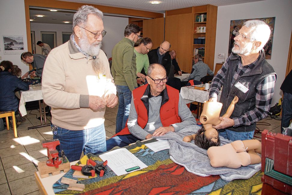 Hans-Jürgen Fritsche (links) und Dieter Lemke (rechts) tüfteln an der Reparatur der Puppe, Besitzer Hermann Ritter blickt kritsch: Viel Hirnschmalz führt zum Erfolg.