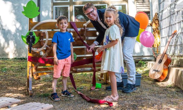 Oberbürgermeister Markus Kleemann mit Kindern vor den neuen Wasserspielwand, einem Jubiläumsgeschenk der Stadt an die Kita.