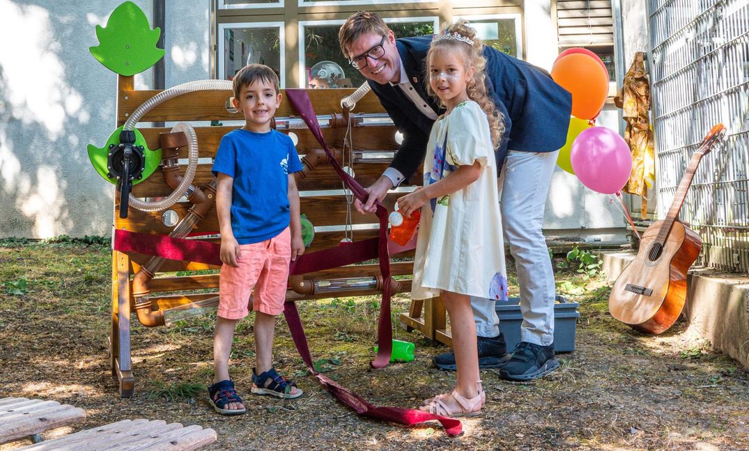 Oberbürgermeister Markus Kleemann mit Kindern vor den neuen Wasserspielwand, einem Jubiläumsgeschenk der Stadt an die Kita.