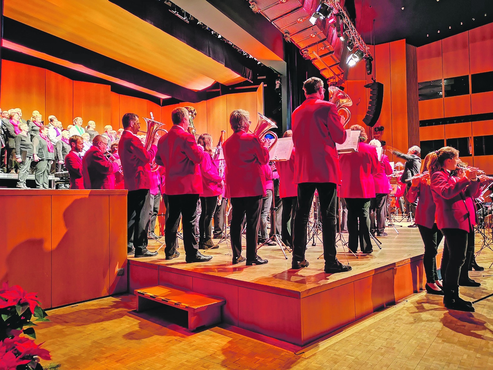 Sänger und Musikanten stehen gemeinsam auf der Bühne der Sindelfinger Stadthalle beim 32. gemeinsamen Weihnachtskonzert von Liederkranz und Stadtkapelle. Markus Nau dirigiert. Bild: Schilpp
