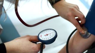 Einem Patienten wird in einer Arztpraxis der Bluthochdruck gemessen.