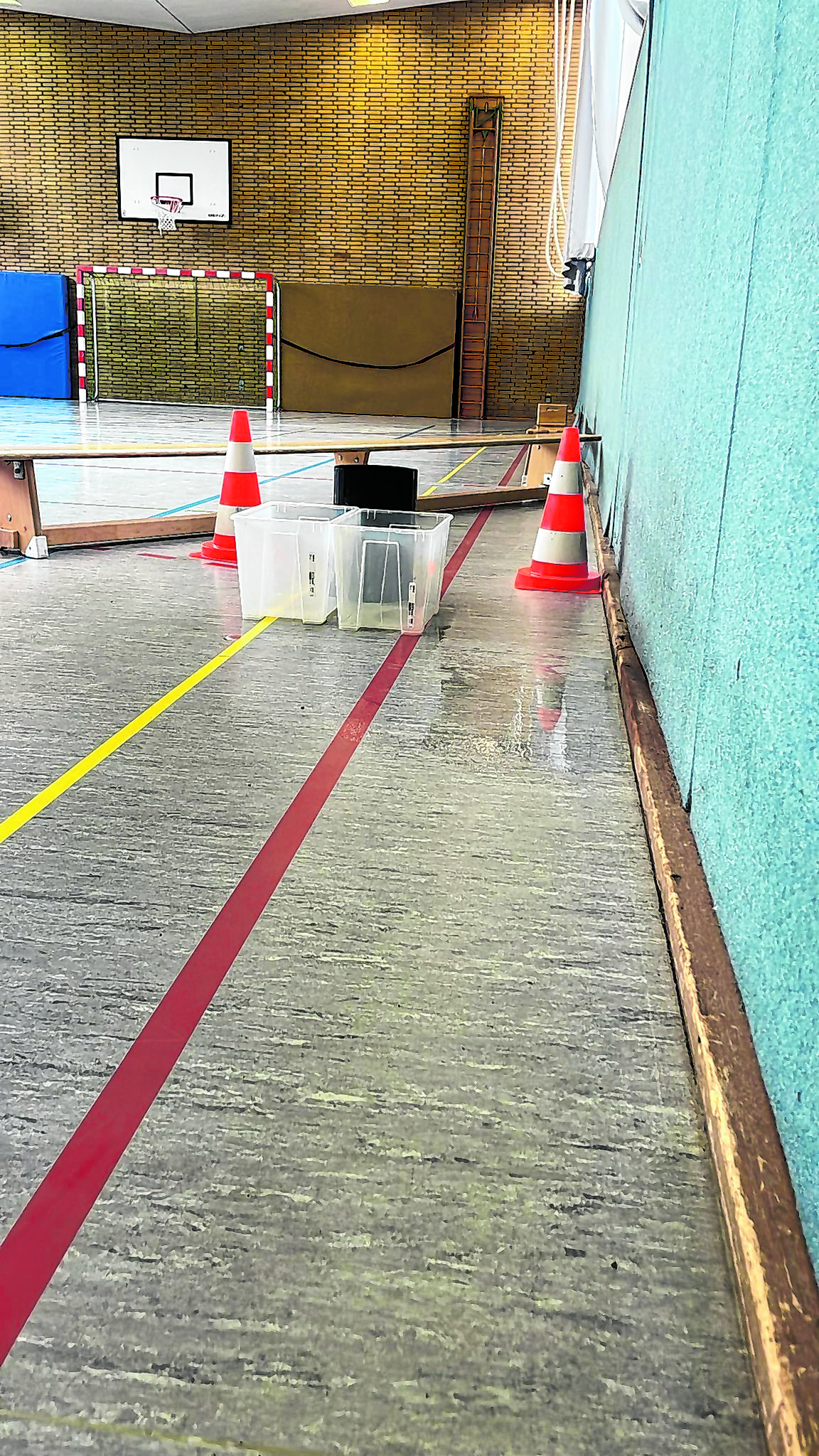 Das Resultat eines undichten Daches: Der Hallenboden ist nass, die feuchte Stelle wird gesperrt, in Plastikkisten werden Wassertropfen gesammelt.