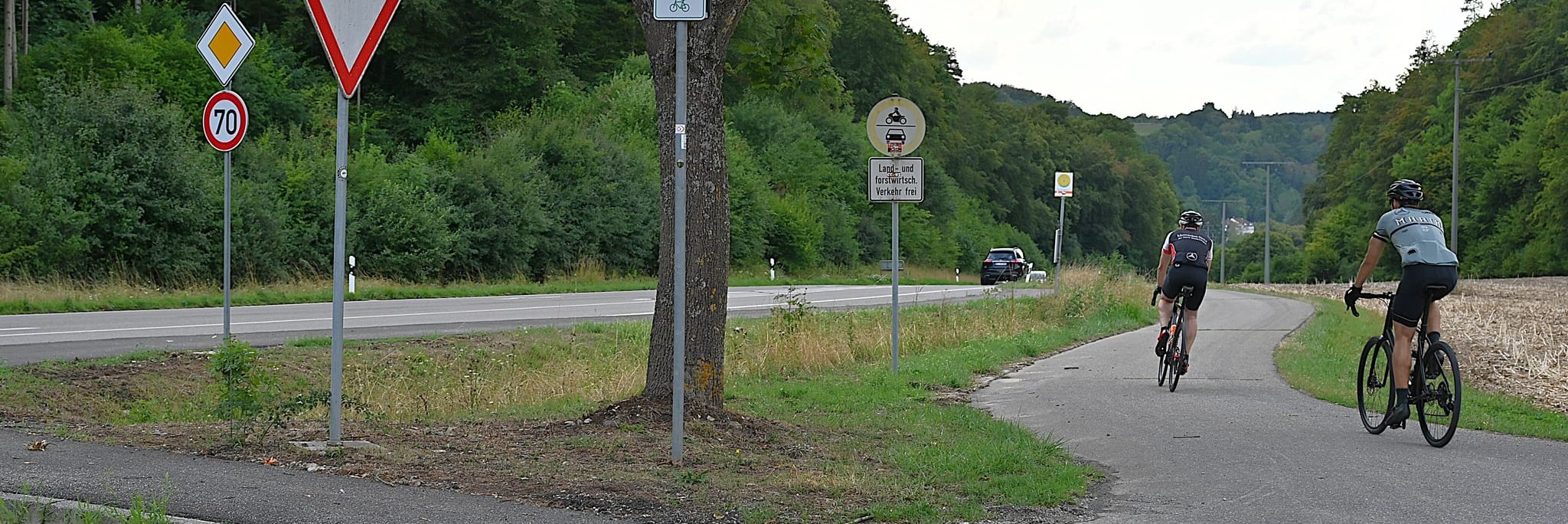 Der obere Einstieg in den neuen Weg an der Zufahrt zum Mutterhaus befindet sich etwa zehn Meter von der Kreisstraße entfernt. Das kleine Schild mit dem Pfeil und dem Fahrradpiktogramm ist nur ein Hinweis auf eine Radroute, aber kein Verkehrszeichen, das d