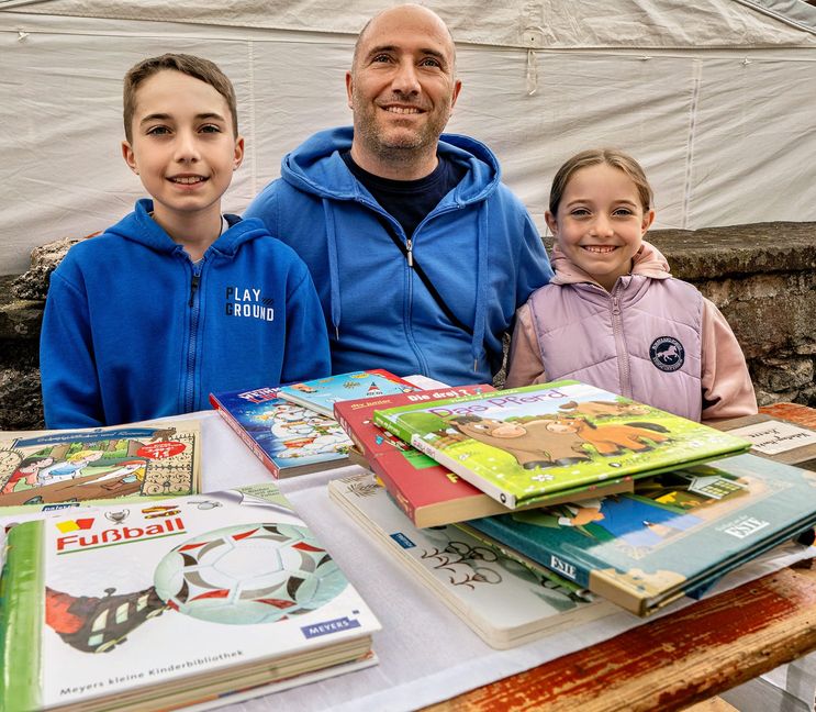 Massimo (12) und Elodie (9) verkaufen beim Flohmarkt, was im Kinderzimmer überflüssig geworden ist. Mit dabei Papa Paolo Sica.
