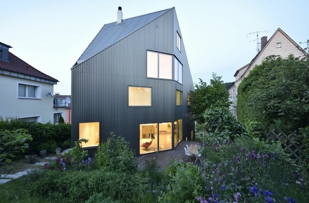 Das Zweifamilienhaus im Stuttgarter Osten von HIIIS Architekten entstand auf einem extremen Hanggrundstück. Mit vorgefertigten Holzständerwänden und BSP-Decken konnte die Bauzeit reduziert werden. Die bronzene Fassade spielt mit wechselndem Licht.