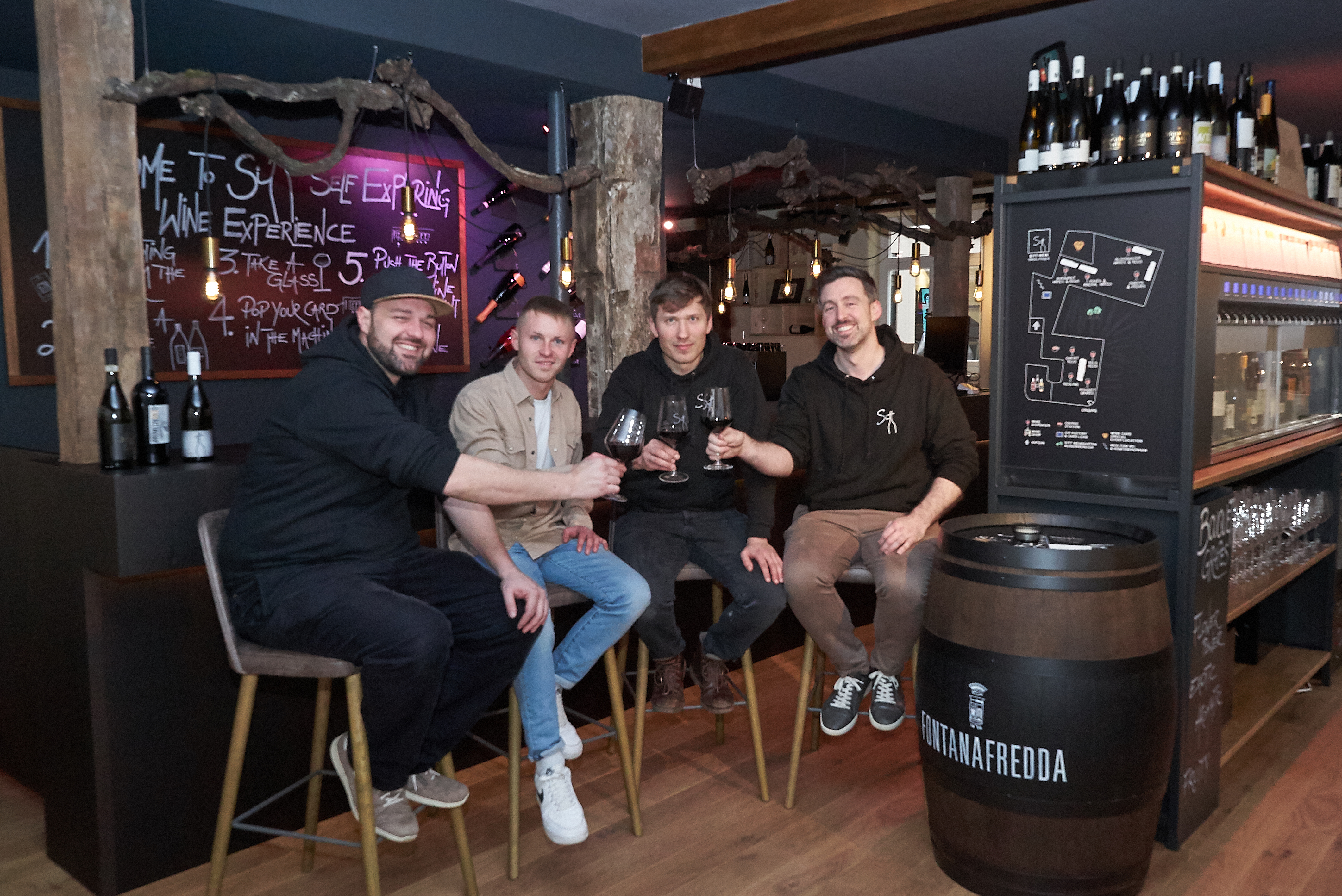 Co-Inhaber Nicolas Sigloch, Wohnstätten-Projektentwickler Oliver Schäfer und die beiden Sitt-Wein-Mitinhaber Christian Dahms und Pablo Dahl stoßen auf die Eröffnung der Weinbar-Weinhandlung in der ehemaligen Traube an (von links).      Bild Heiden