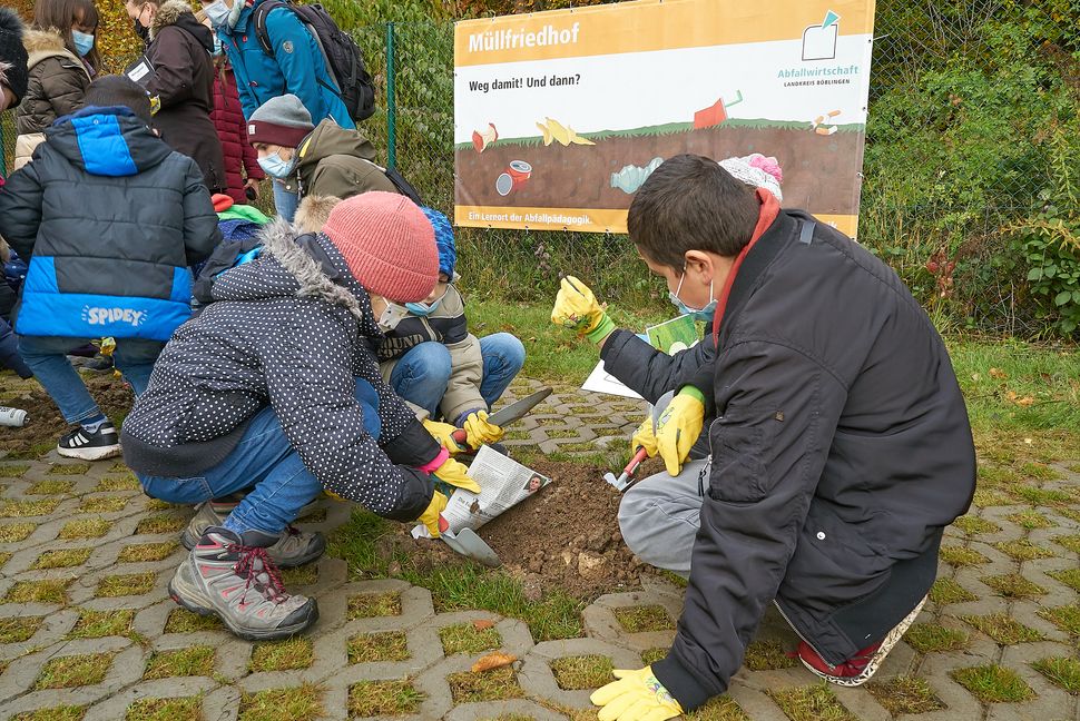 Zur Einweihung des Sindelfinger "Müllfriedhofs" reiste die Klasse 3b der Paul-Lechler-Schule dafür eigens aus Böblingen an. Hier wird eine Zeitung vergraben.           Bild: Heiden