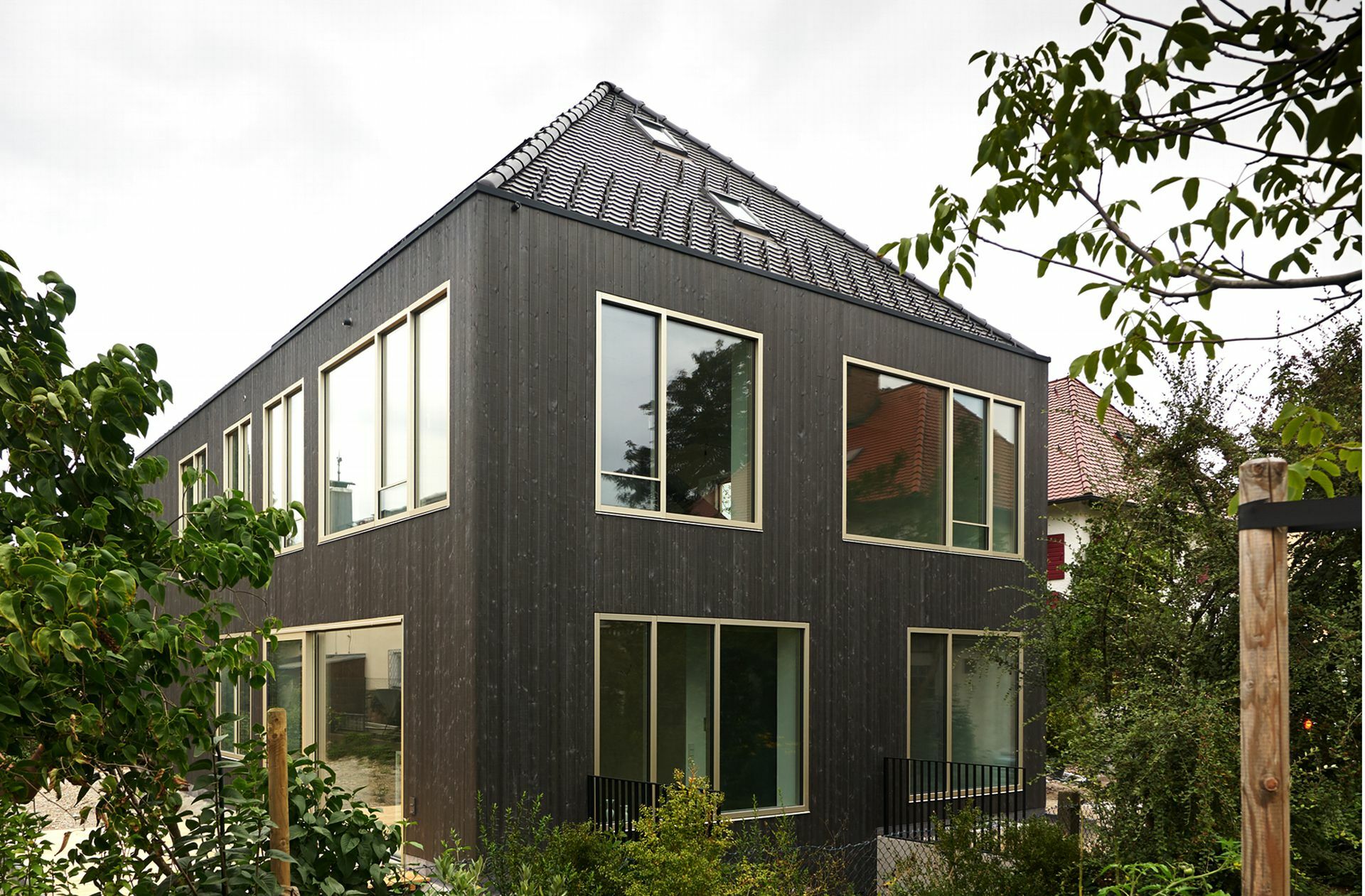 Die   Holzfassade ist schwarz lasiert. Der Grund: „Das Gebäude sollte sich elegant zurücknehmen“, sagt der Architekt Stephan Rauch, zu den vorne liegenden Bestandsgebäuden nicht in Konkurrenz treten: „Durch die dunkle Farbe ist es schon in der Dämmerung kaum mehr auszumachen und verschmilzt mit der Natur.“
 Foto: Claudius Müller