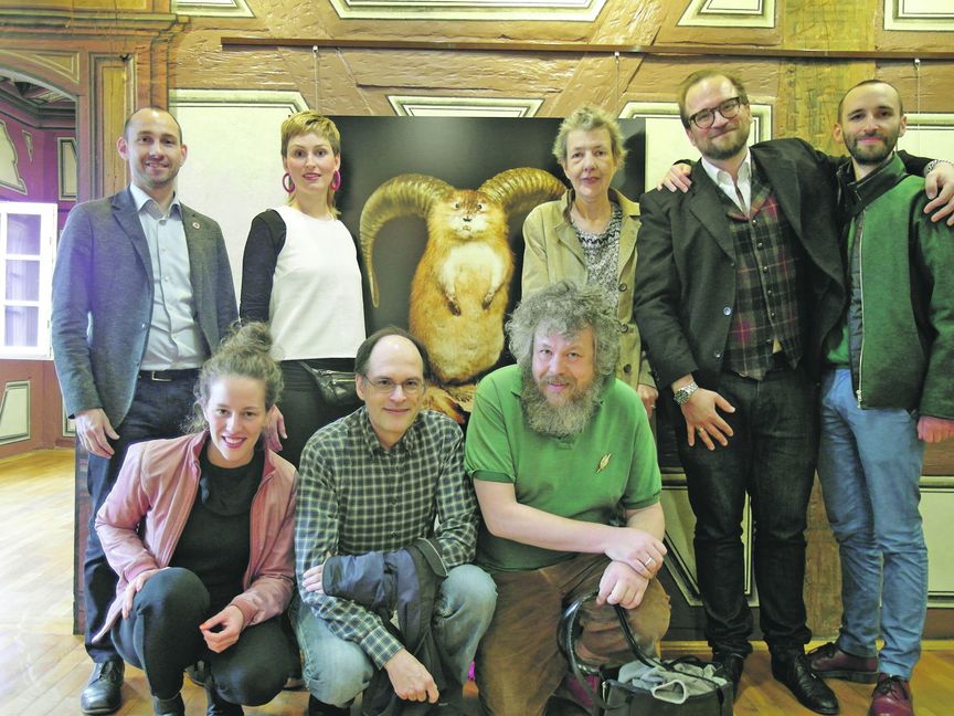 Bei der Eröffnung der Sonderausstellung „Eierlegende Wollmilchsau“ im Fleischermuseum (von links stehend) Oberbürgermeister Dr. Stefan Belz, Lea Dohle, Julia Schrader, Museumsleiter Dr. Christian Baudisch, Lukas Betzler, (von links sitzend) Katharina Bourjau, Martin Frei und Hans Pfrommer. Dahinter die Fotografie „Gehörnte Bisamratte“ von Volker Weinhold und Sebastian Köppke. Bild: Staber