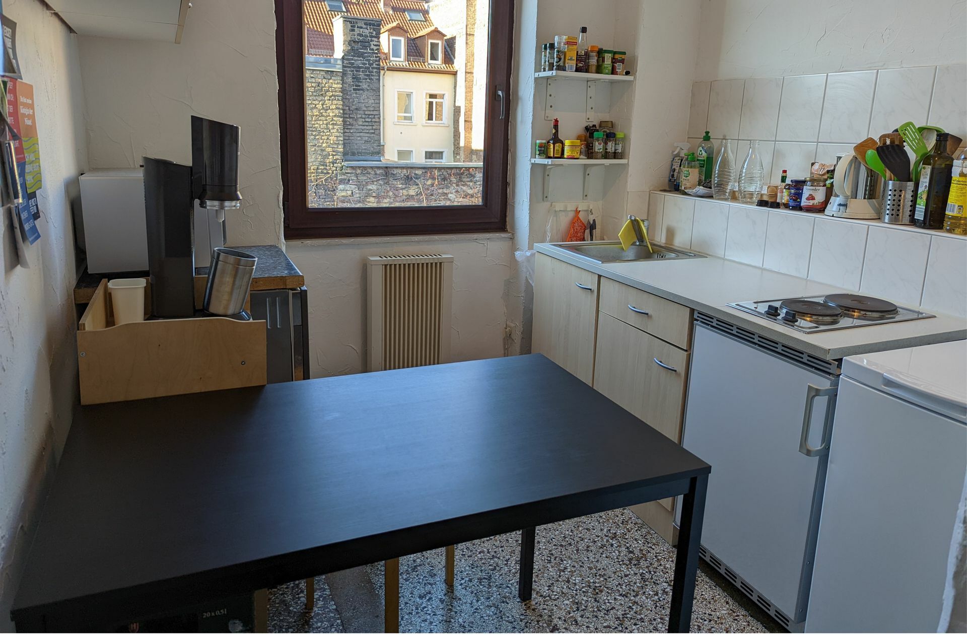 In der Küche gibt es einen Kühlschrank und zwei Elektroplatten zum Kochen. Außerdem steht dort auch eine notdürftig abgetrennte Dusche, in der sich alle waschen.