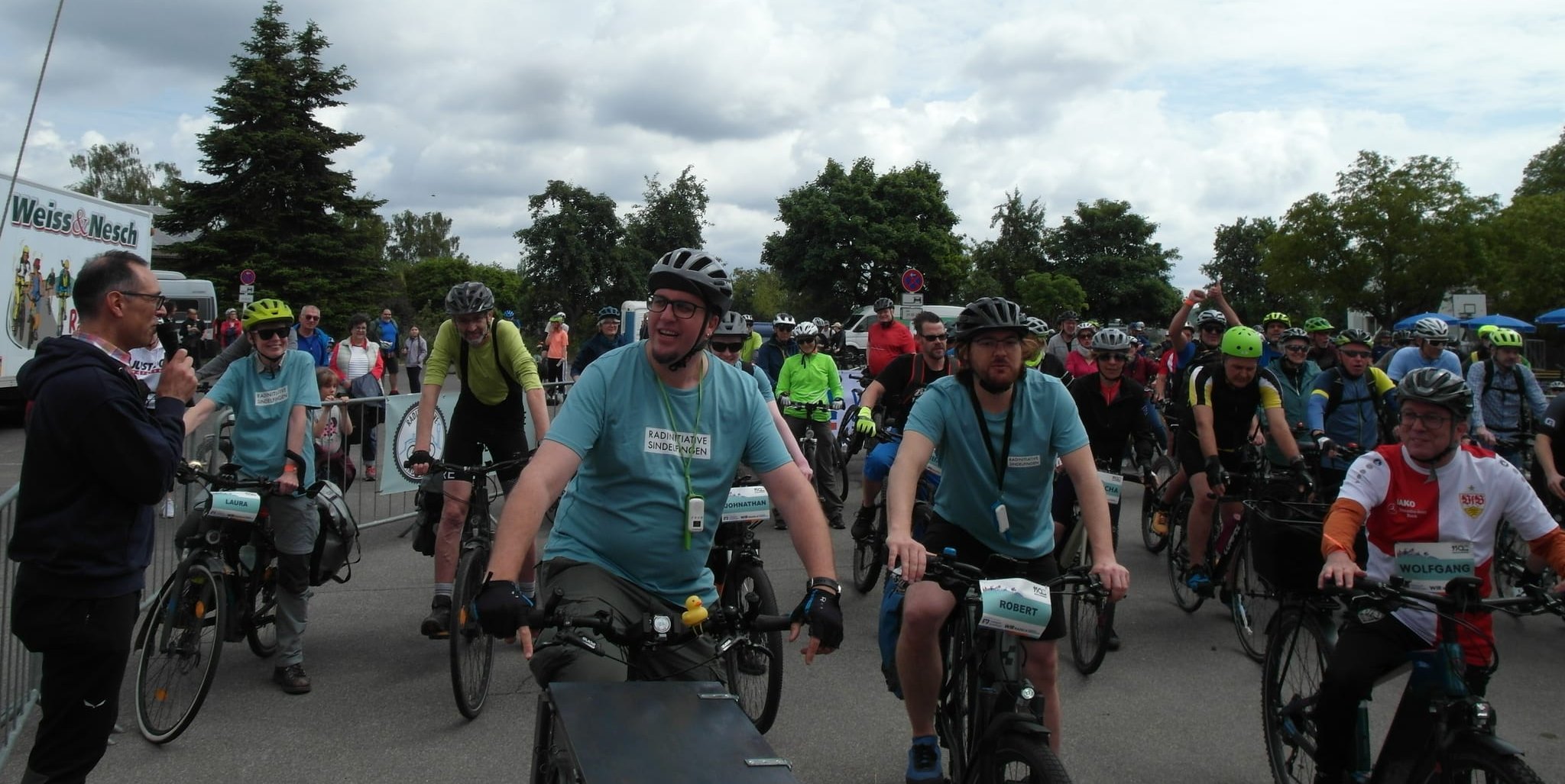 Organisator Albrecht Röder (links, mit Mikro) und Maichingens Ortsvorsteher Wolfgang Stierle (rechts, mit VfB-Trikot) beim Start der „Jubiläums-Radtour von Maichingen nach Hirsau“ im Rahmen des Festprogramms „950 Jahre Maichingen“. Bild: Staber