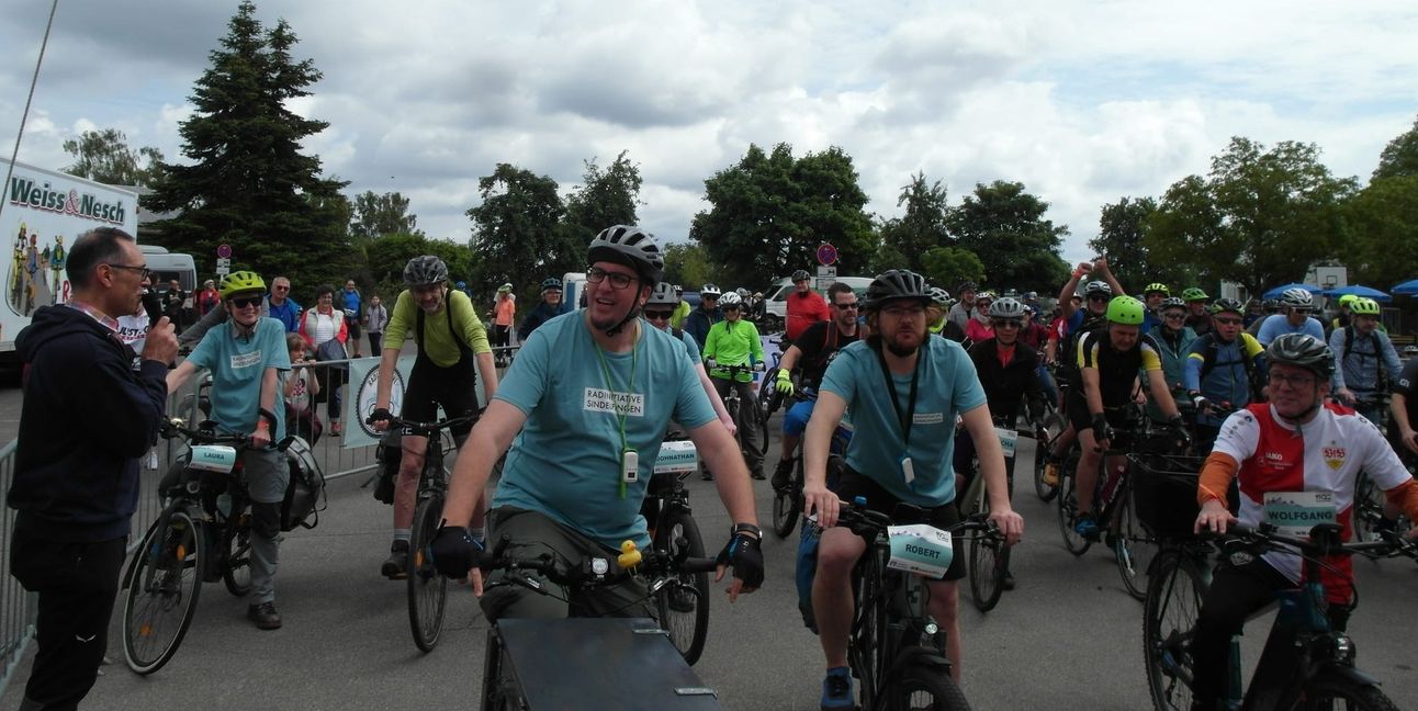 Organisator Albrecht Röder (links, mit Mikro) und Maichingens Ortsvorsteher Wolfgang Stierle (rechts, mit VfB-Trikot) beim Start der „Jubiläums-Radtour von Maichingen nach Hirsau“ im Rahmen des Festprogramms „950 Jahre Maichingen“. Bild: Staber