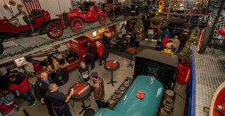 In der weihnachtlich geschmückten Fahrzeughalle des Oldtimermuseums in Aidlingen erklärt Reiner Wilhelm (vorne im schwarzen T-Shirt) den Besuchern seine Fahrzeuge.