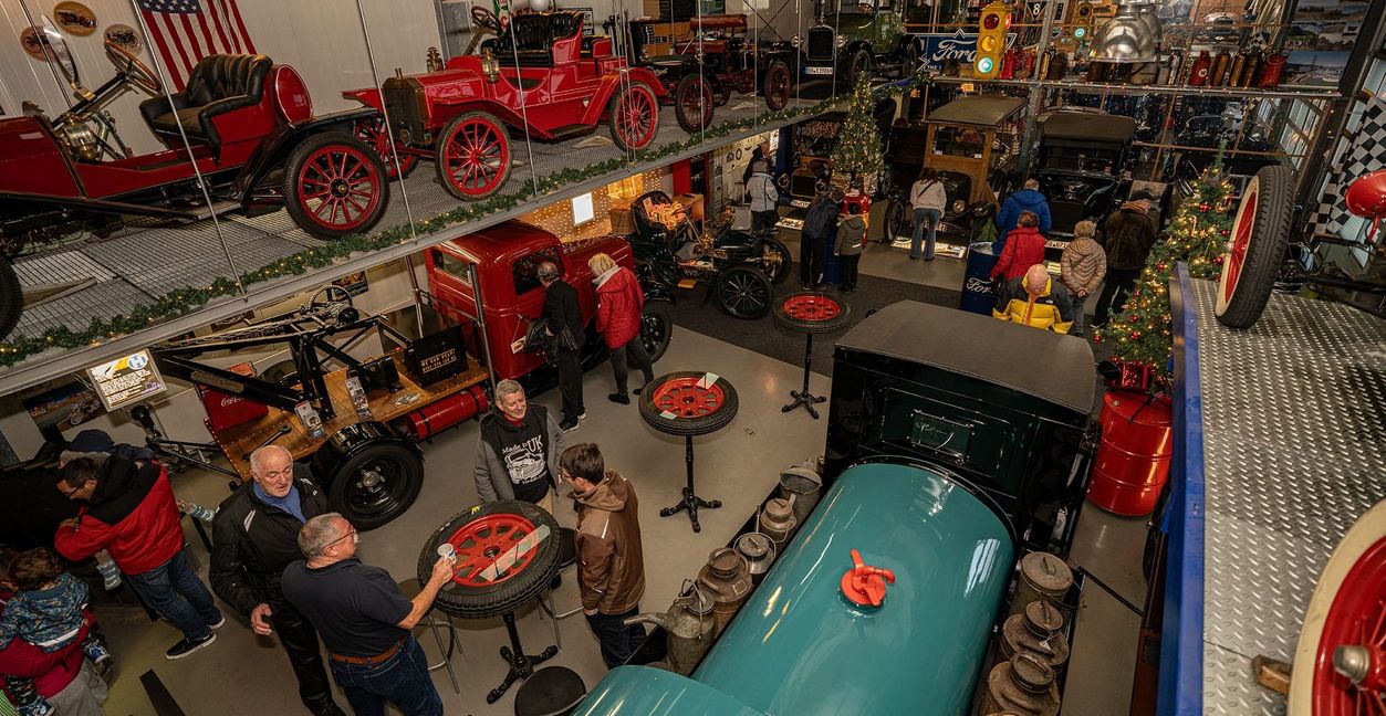 In der weihnachtlich geschmückten Fahrzeughalle des Oldtimermuseums in Aidlingen erklärt Reiner Wilhelm (vorne im schwarzen T-Shirt) den Besuchern seine Fahrzeuge.