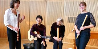 Diverse Flöten sowie die Saiten einer Gitarre ergeben das Motto „Holz trifft Saiten“.