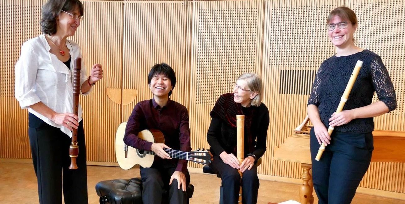 Diverse Flöten sowie die Saiten einer Gitarre ergeben das Motto „Holz trifft Saiten“.