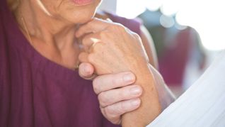 Eine Frau hält die Hand ihres an Demenz erkrankten Mannes.