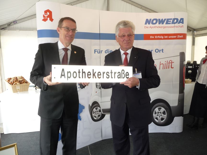 Böblingens Oberbürgermeister Wolfgang Lützner (links) überreicht dem Vorstandsvorsitzenden der Noweda anlässlich des Spatenstichs das Straßenschild mit der neuen Adresse für die Böblinger Niederlassung der Genossenschaft.	Bild. Reichert