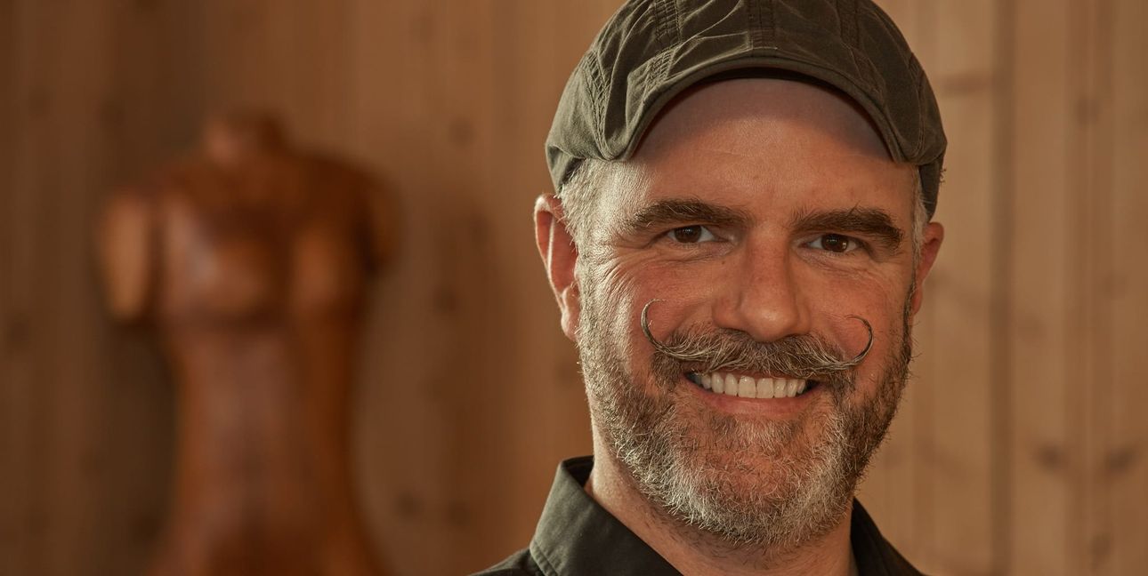 Dominik Heinkele mit einer von seinen Skulpturen im Hintergrund.