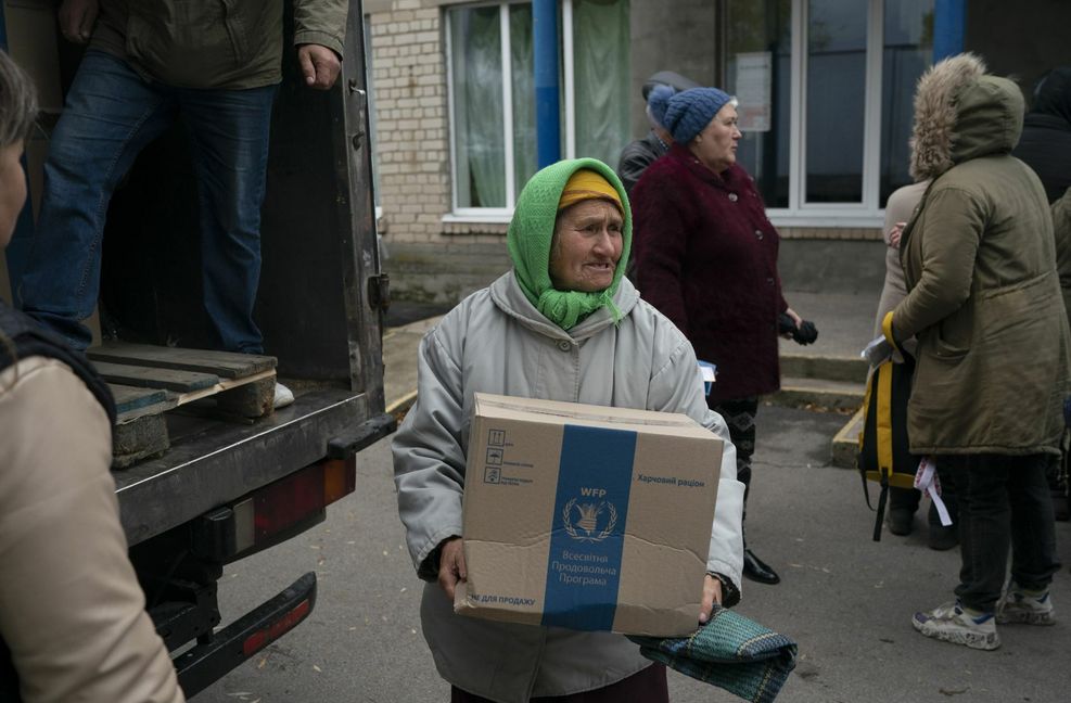 Eine Ukrainerin bekommt bei einer Hilfsaktion eine Kiste mit Spenden.