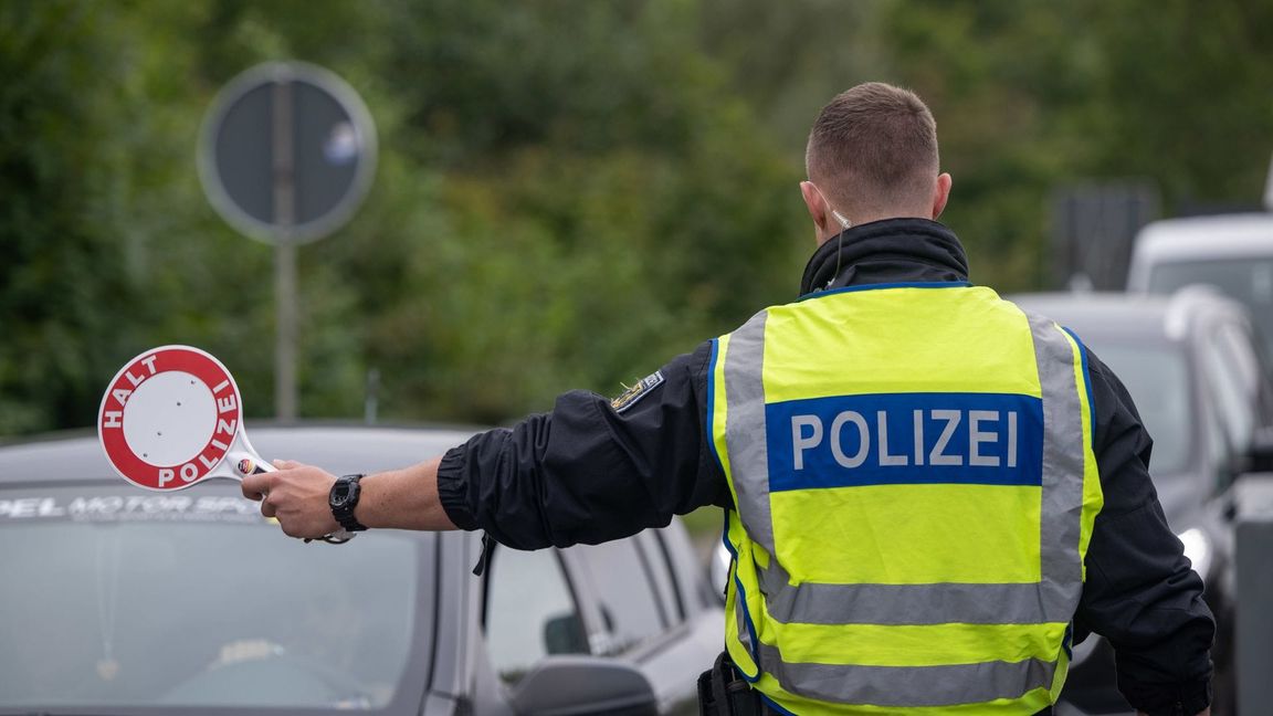 Ein Polizist hält Fahrzeuge an der Grenze zu Deutschland an.