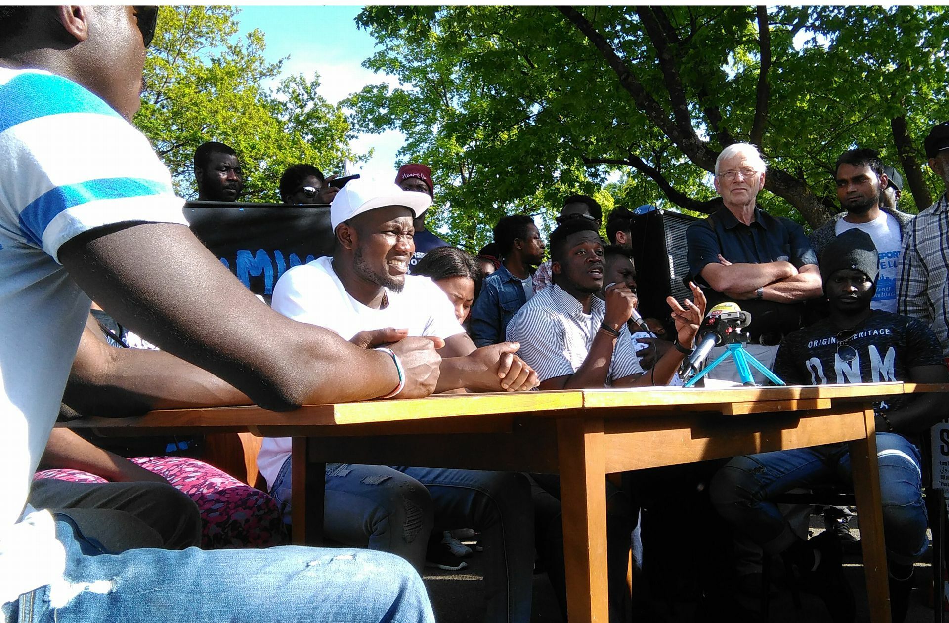 Alassa Mfouapon (mit Mikrofon) bei einer improvisierten Pressekonferenz vor der Landeserstaufnahmestelle in Ellwangen. Foto: /Wein