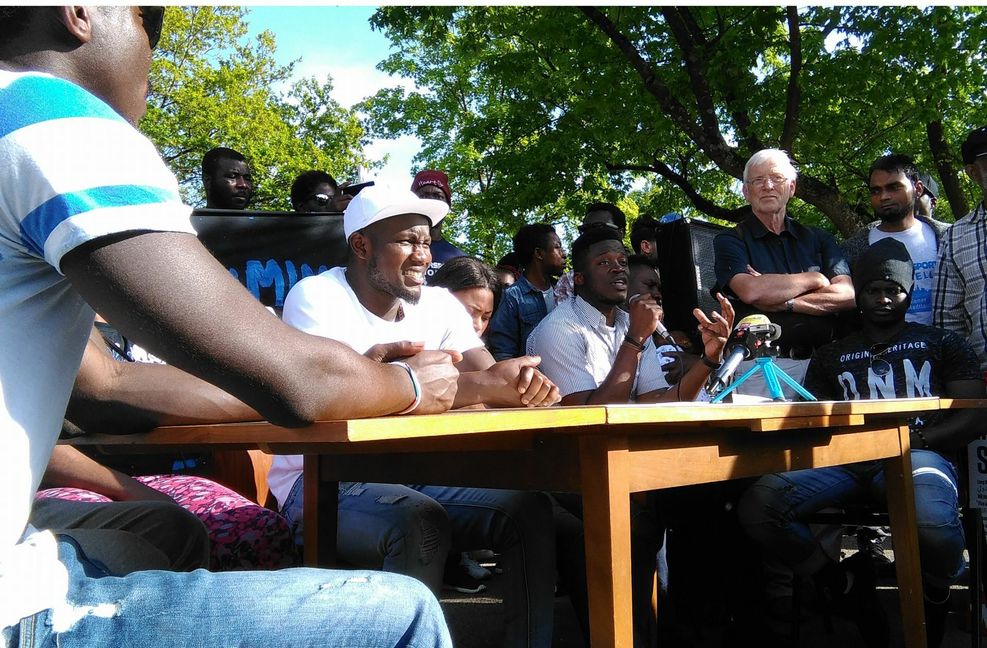Alassa Mfouapon (mit Mikrofon) bei einer improvisierten Pressekonferenz vor der Landeserstaufnahmestelle in Ellwangen. Foto: /Wein