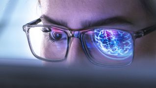 Ein Arzt untersucht mit Hilfe einer KI die Abbildung eines menschlichen Gehirns.