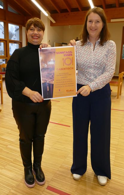 Roxana Parlapanis (links) und Bettina Hartig präsentieren das Poster für das Sonntagsessen. Bild: Lück