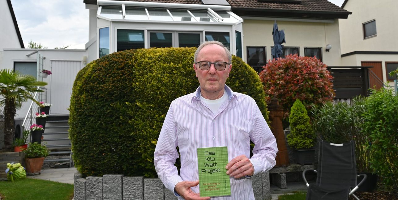 Manfred Maurer mit seinem Taschenbuch über die eigene Energiewende. Im Hintergrund die Doppelhaushälfte mit der PV-Anlage. Solarpaneele wurden natürlich auf der Südseite, aber auch auf der Nordseite und auf dem Garagendach installiert