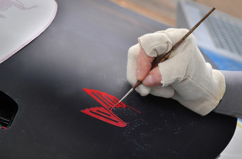 Handarbeit für filigrane Details: Die Konturen eines geflügelten Pferds entstehen als Schmuckelement auf einem Porsche.