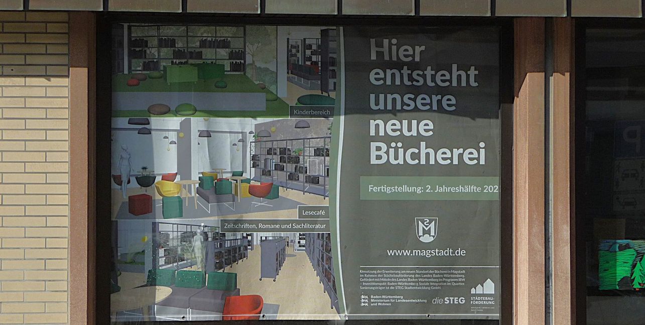 Das Plakat hängt schon im Schaufenster des Gebäudes gegenüber von der Bücherei und zeigt, wie es nach dem Umbau und dem Umzug innen aussehen könnte. Bild: Reichert