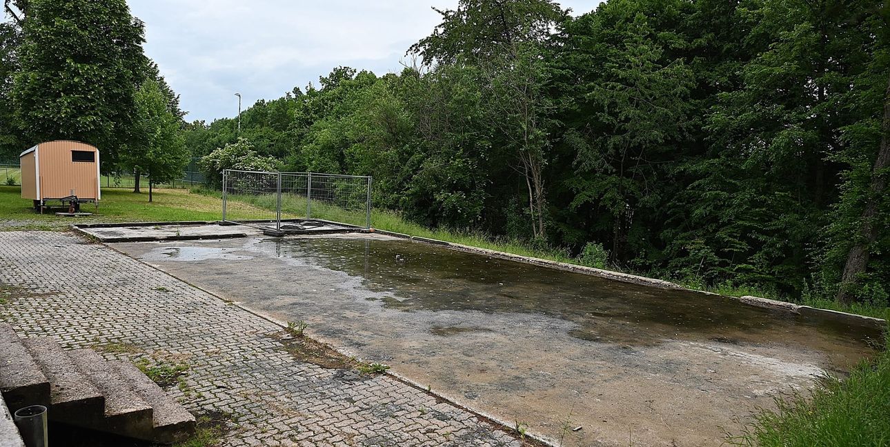 Auf dem Fundament der abgebrannten Blockhütte steht das Wasser. Im Hintergrund der Toilettenwagen, der beim Brand weitgehend unbeschädigt blieb.