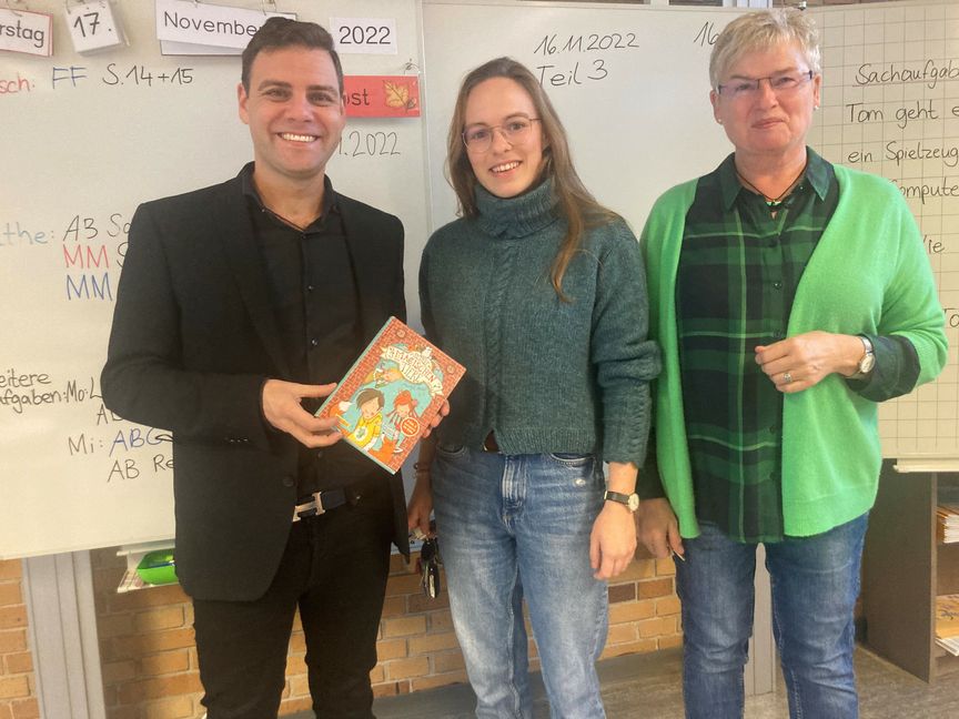 Landtagsabgeordneter Florian Wahl, Klassenlehrerin Eva Schilpp und Rektorin Barbara Knöbl finden es wichtig, dass Kindern vorgelesen wird. Eva Schilpp hat für den Vorlesetag ein unterhaltsames Buch ausgewählt. Bild: Gospodarczyk