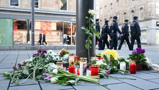 Kerzen und Blumen liegen in der Nähe des Paradeplatzes in Mannheim an einer Straßenbahnhaltestelle. (Archivfoto)