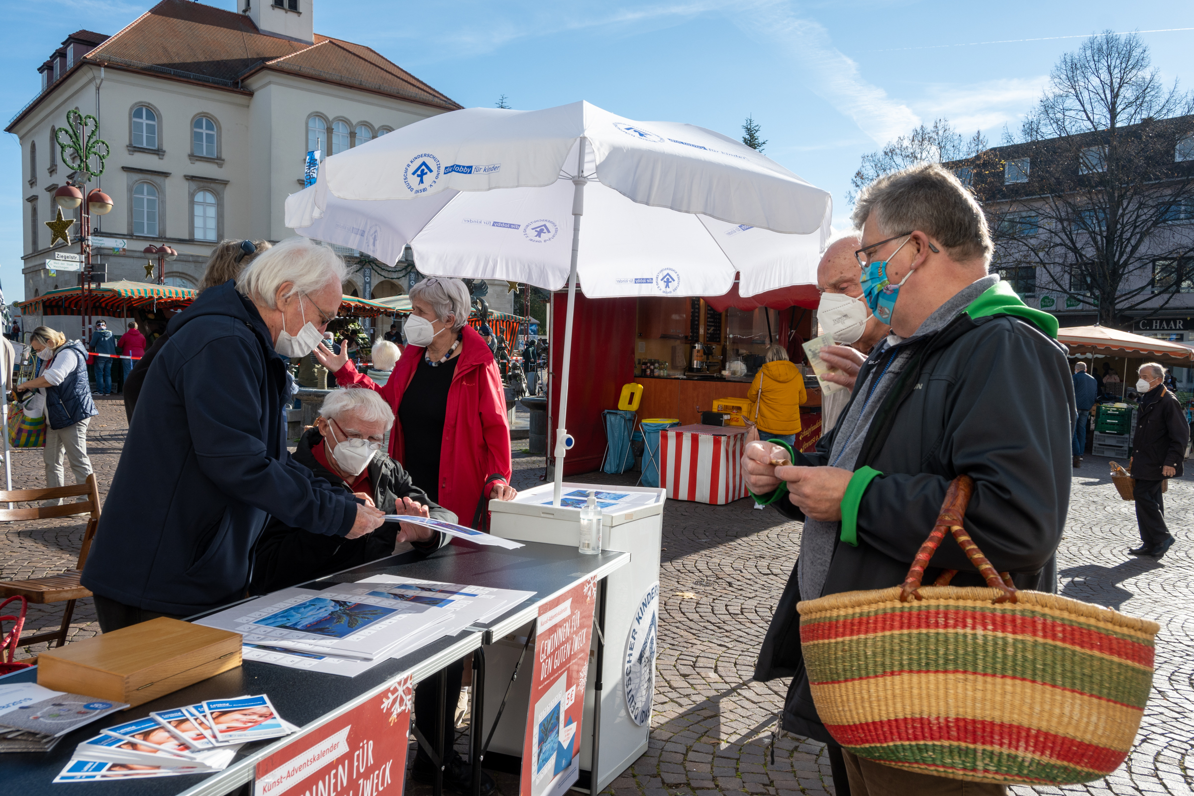 Hans Bäurle (sitzend) signierte den diesjährigen Adventskalender des Kinderschutzbundes auf dem Wochenmarkt.