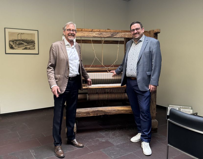 Michael Georgii (links, Geschäftsführer von Zweigart & Sawitzki) und Felix Rapp (Geschäftsführer 
der WSG) vor einem Webstuhl aus dem 18. Jahrhundert im Foyer des Sindelfinger Unternehmens.