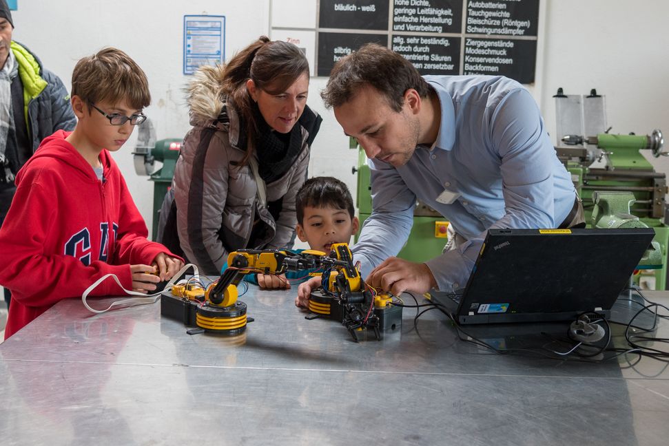 Matthias Müller (rechts) erläutert den Besuchern die Funktionsweise von Roboterarmen.