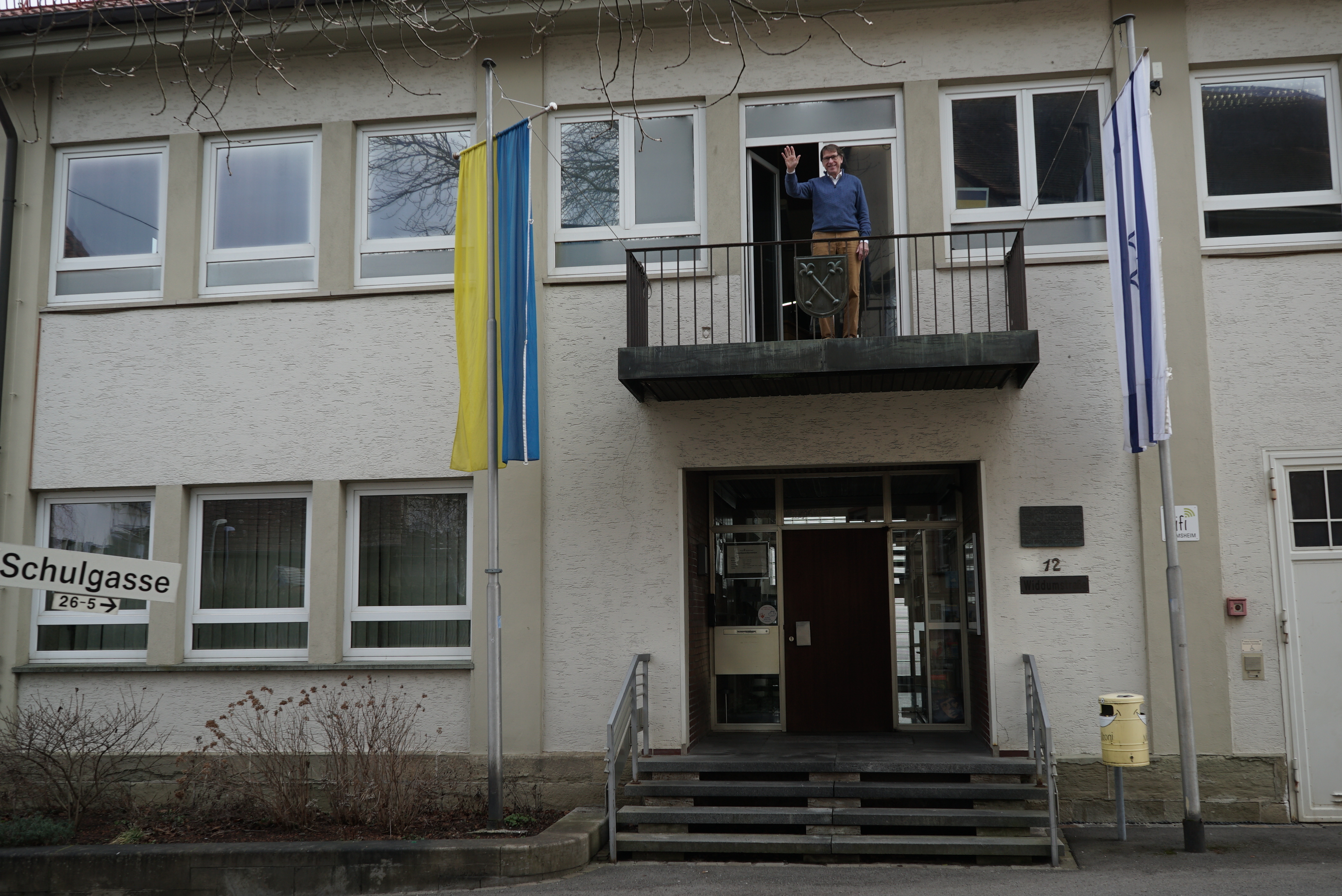 An die Außentreppe des Bezirskamts soll eine Liftplattform. Bei Ortsvorsteher Lambert, der vom Balkon winkt und der Verwaltung im 1. Stock, ist man damit noch lange nicht. Bild: Heiden