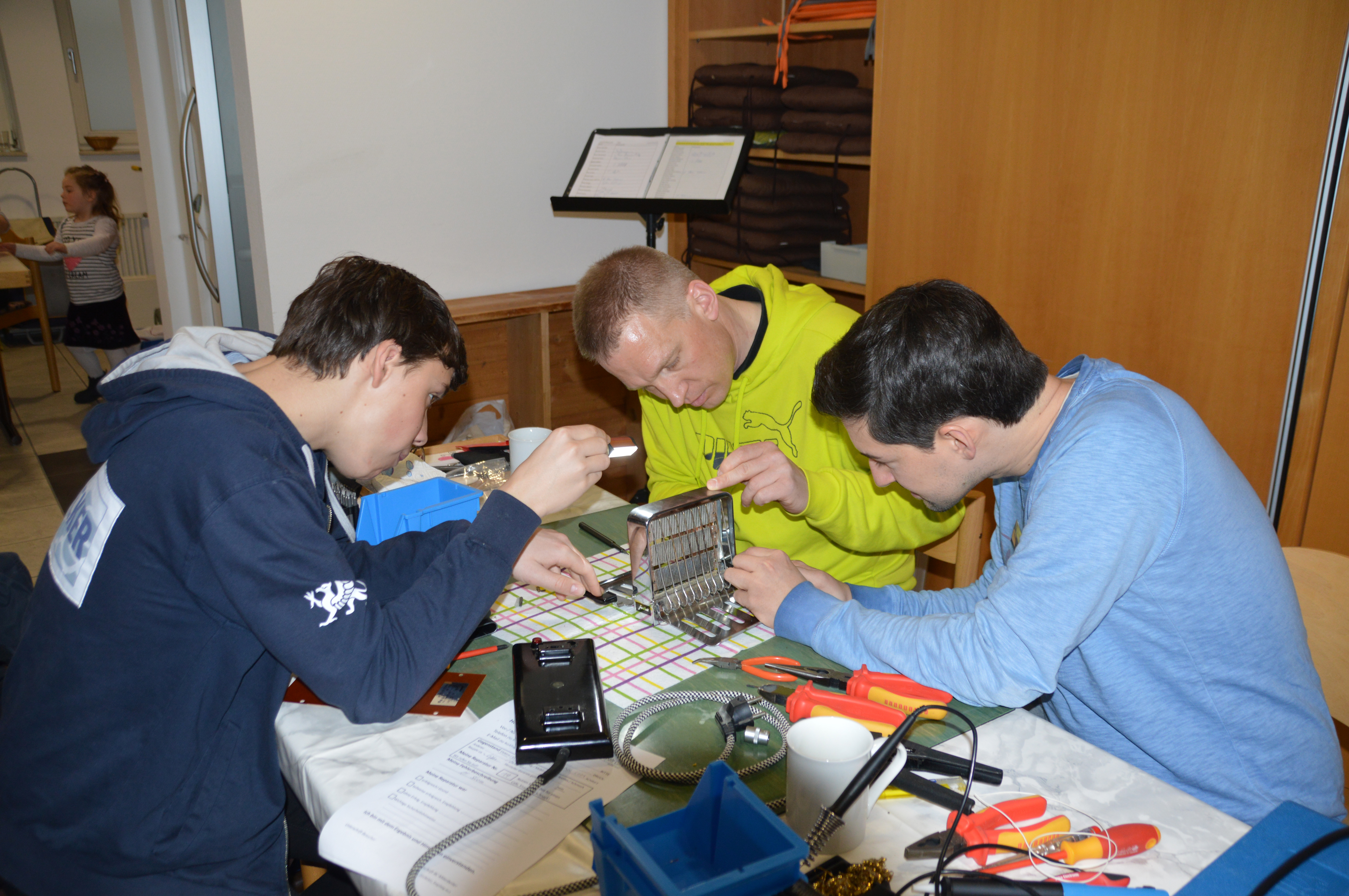Besucher Benno Meyer und Reparierer Arne Heemeshoff und Johannes Kern (von links) nehmen den defekten Retro-Toaster genauer unter die Lupe. Bilder: Groß