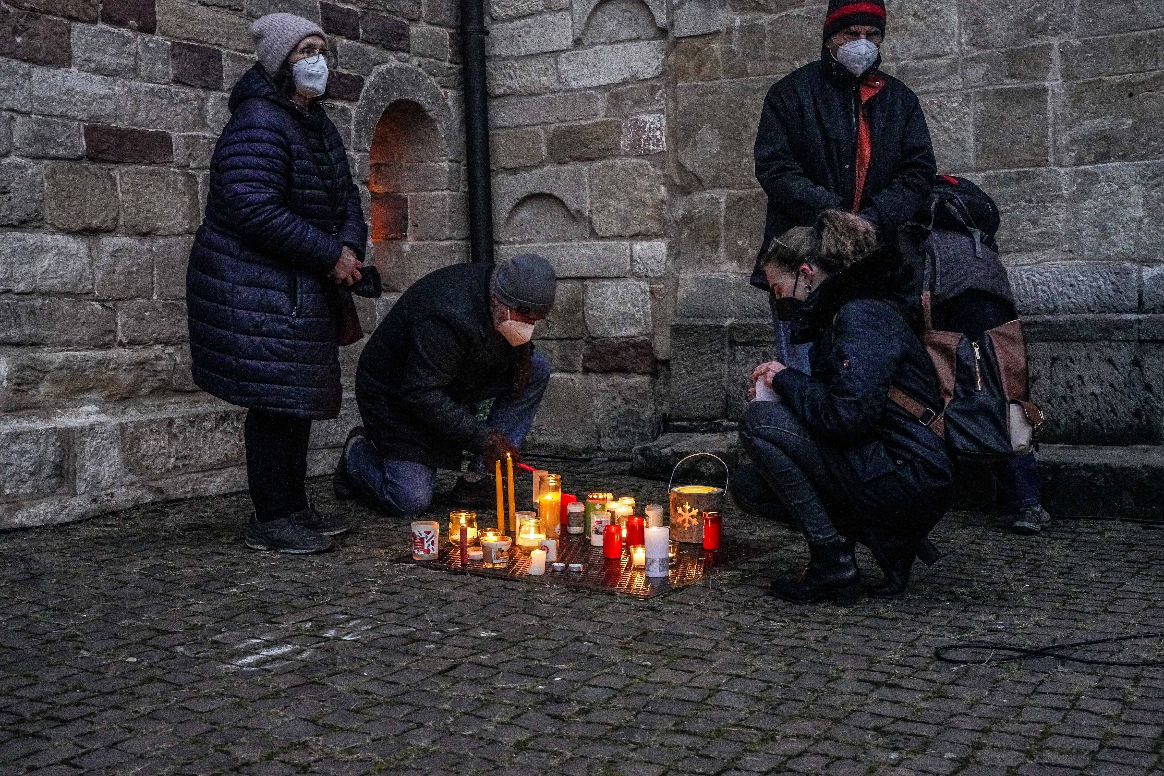In der windgeschützten Ecke vor der Martinskriche zünden die Teilnehmer der Gedenkfeier ihre Kerzen. Bild: Dettenmeyer