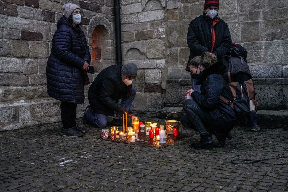 In der windgeschützten Ecke vor der Martinskriche zünden die Teilnehmer der Gedenkfeier ihre Kerzen. Bild: Dettenmeyer