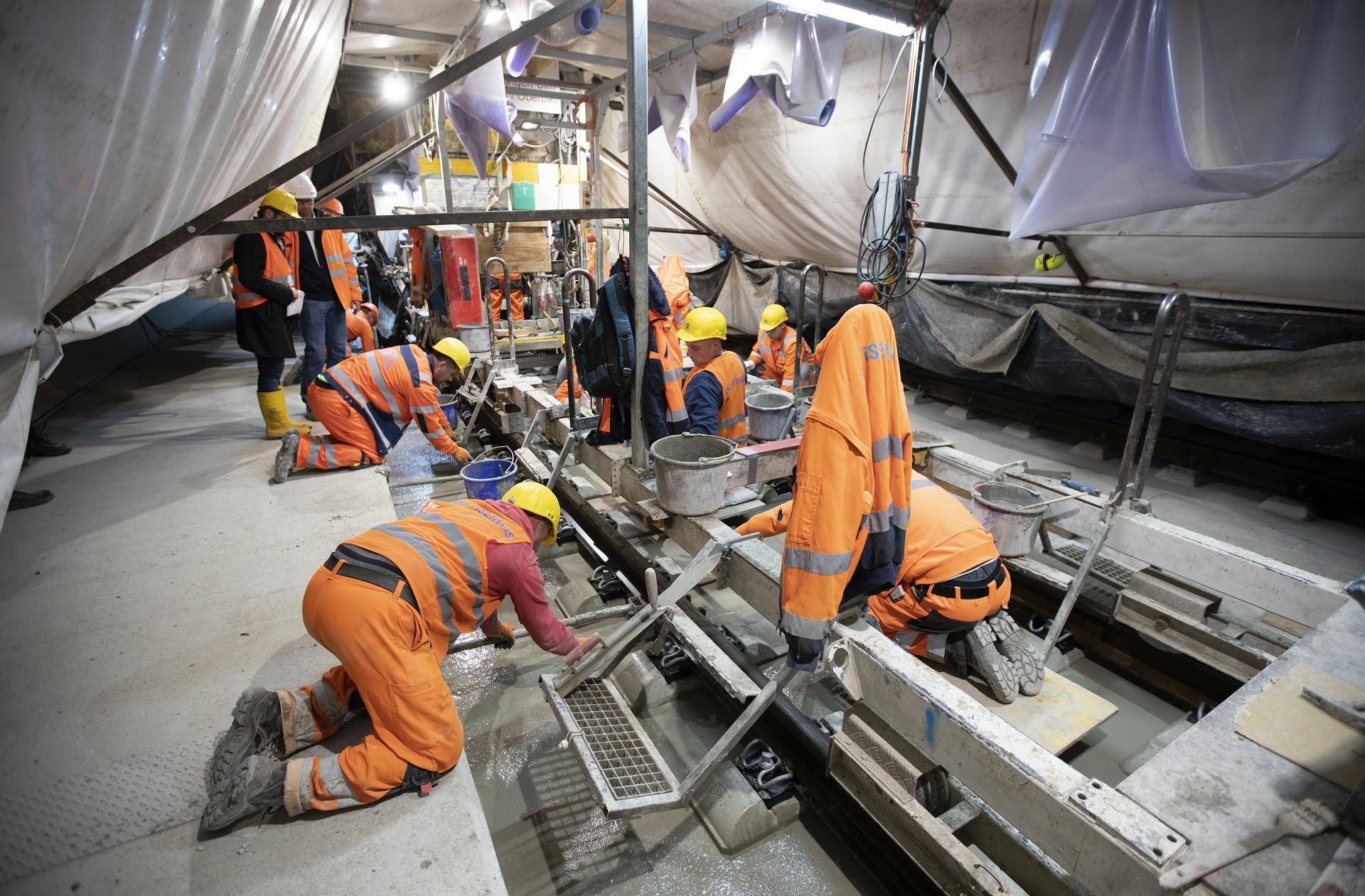In einem nächsten Schritt werden die Schwellen in Beton eingegossen. Die Arbeiter ziehen die Oberfläche glatt und rutschen auf Knien der wandernden Baustelle hinterher.