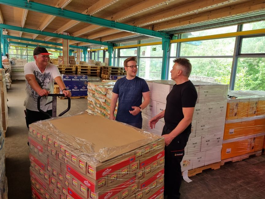 Der ehrenamtliche Helfer Holger Stark (von links) karrt eine neue Palette Lebensmittel ins Lager der Klosterseehalle, in dem Maximilian Reinhardt und Feuerwehrmann Peter Neumann gerade den Warenbestand besichtigen. Beide sind sich darin einig, dass „Helfen statt Hamstern“ dringend auf weitere Spenden aus der Bevölkerung angewiesen ist, um den Menschen in der Ukraine und Kriegsflüchtlingen, die hierherkommen, in bewährter Form humanitäre Hilfe zukommen lassen zu können. Bild: Hamann