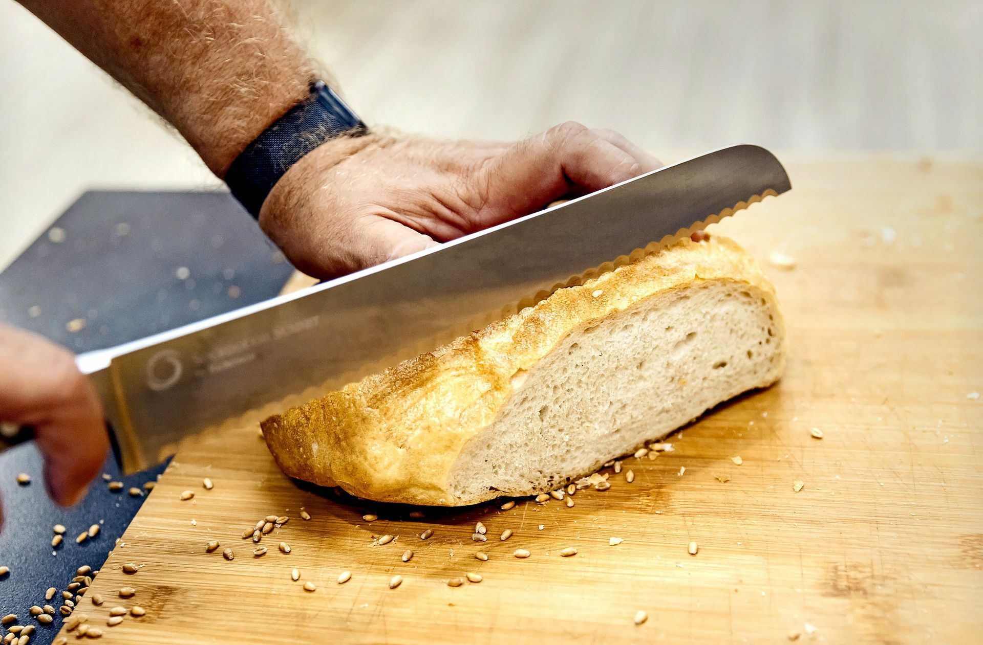Bäcker Heiner Beck schneidet ein Brot aus Futtergetreide auf.